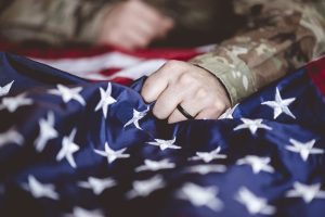 American soldier mourning and praying with the American flag in front of him Additional Condition(s)